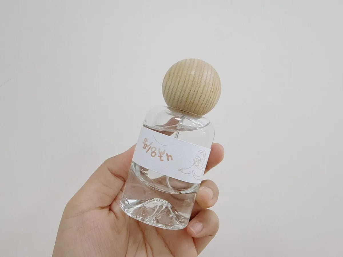Slow Sloth perfume bottle with round wooden cap and hill-shaped glass base